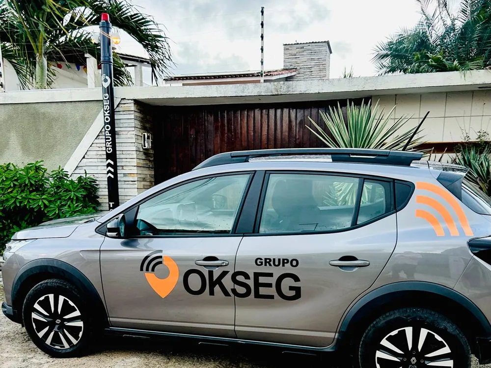 Viatura do Grupo OKSEG estacionada ao lado de um totem de segurança com giroflex